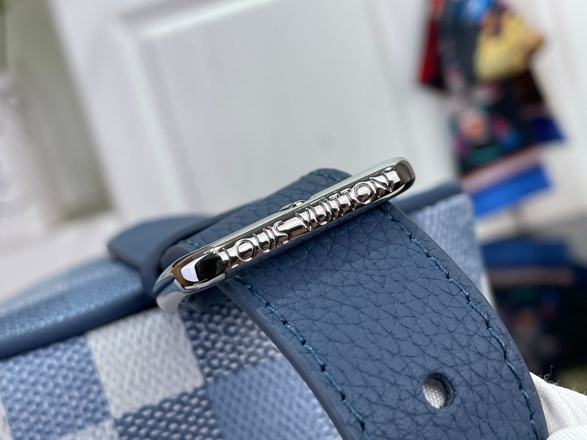 Brushed metal zipper pull on textured blue bag