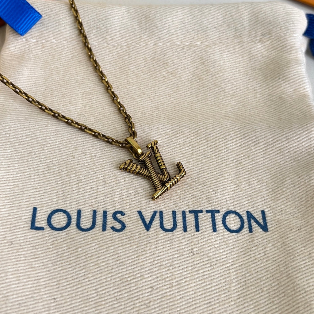 Gold-tone Louis Vuitton necklace pendant on beige dust bag