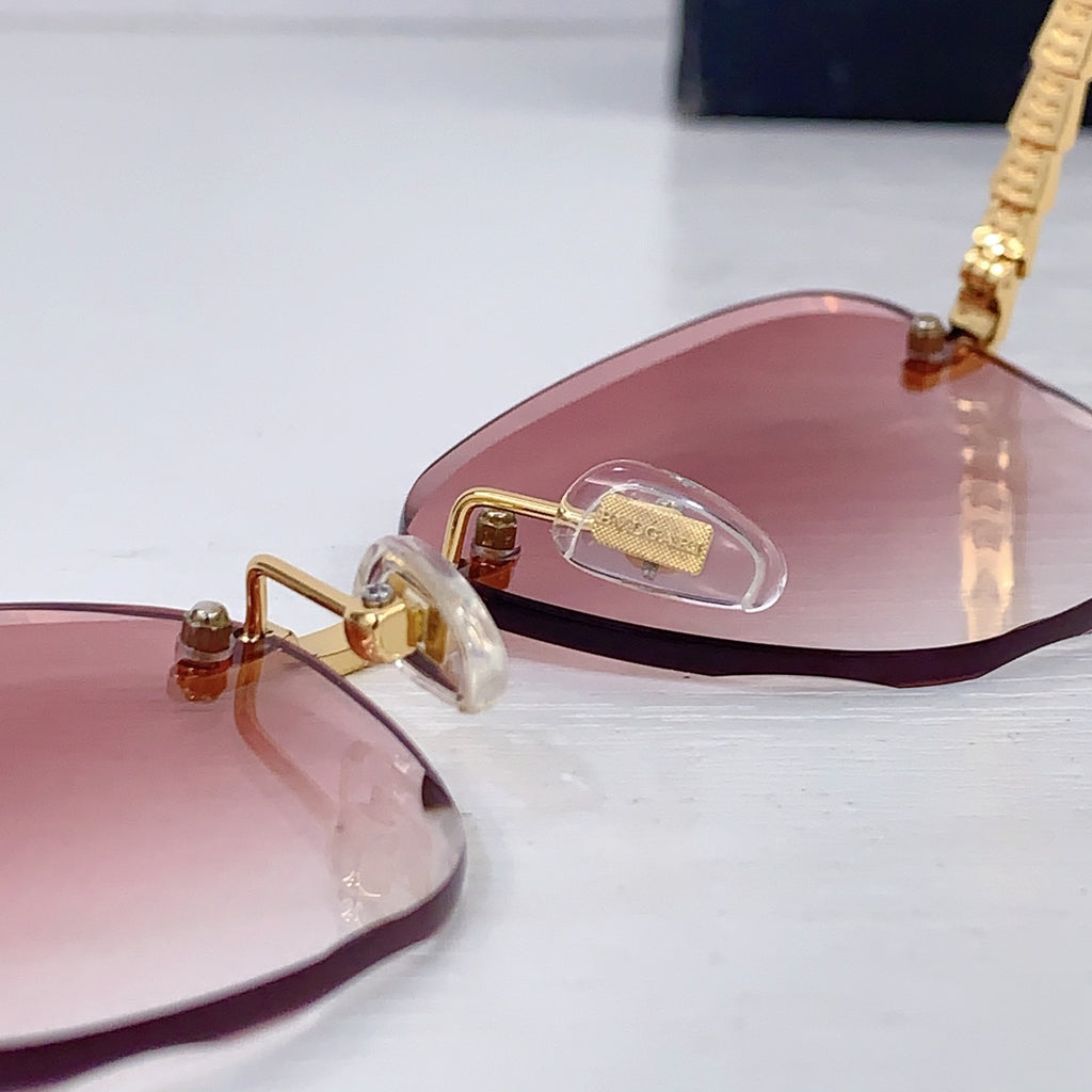 Bvlgari sunglasses side view with pink tinted lenses and gold temple details.