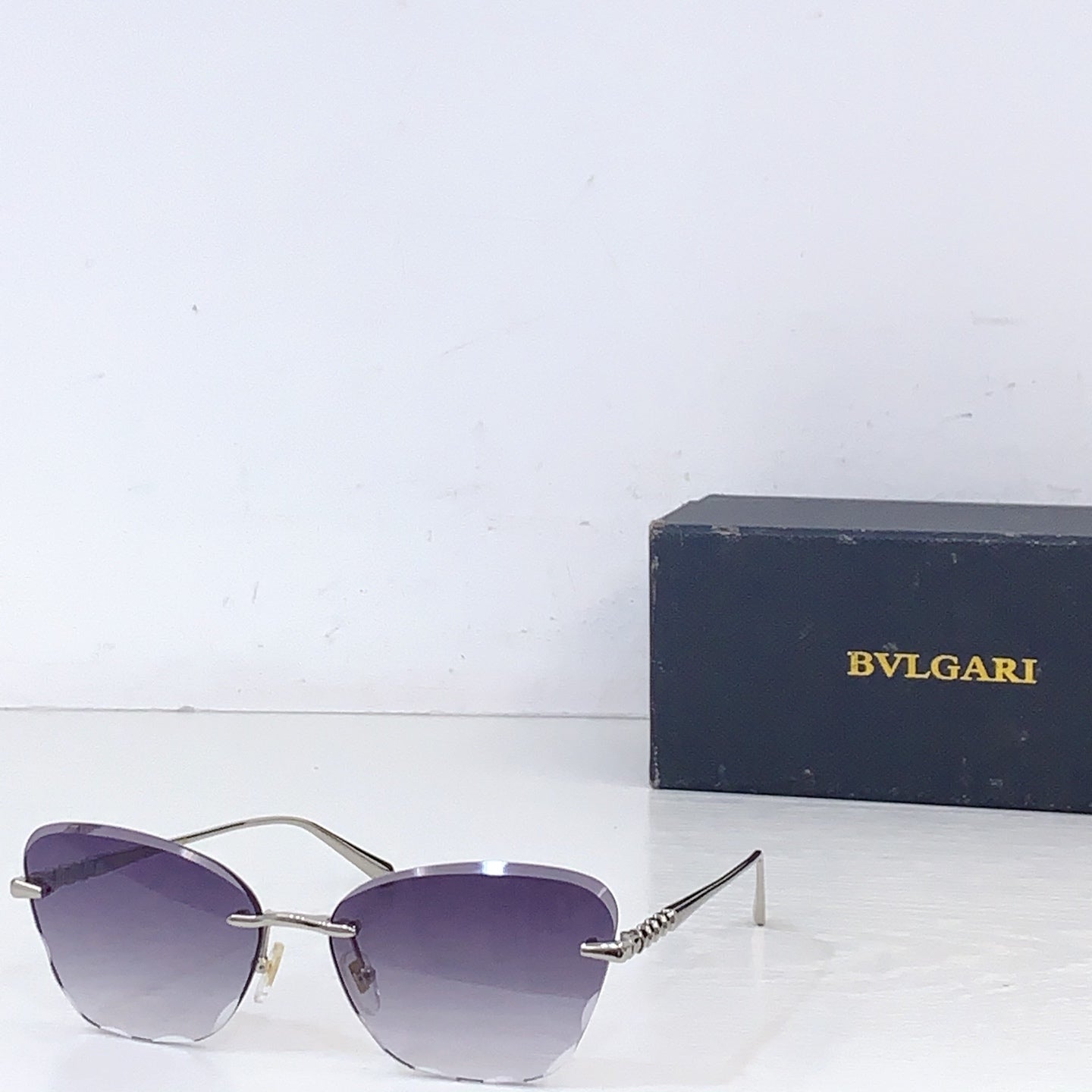 Bvlgari sunglasses with gold metal frame and purple tinted lenses, front angle.