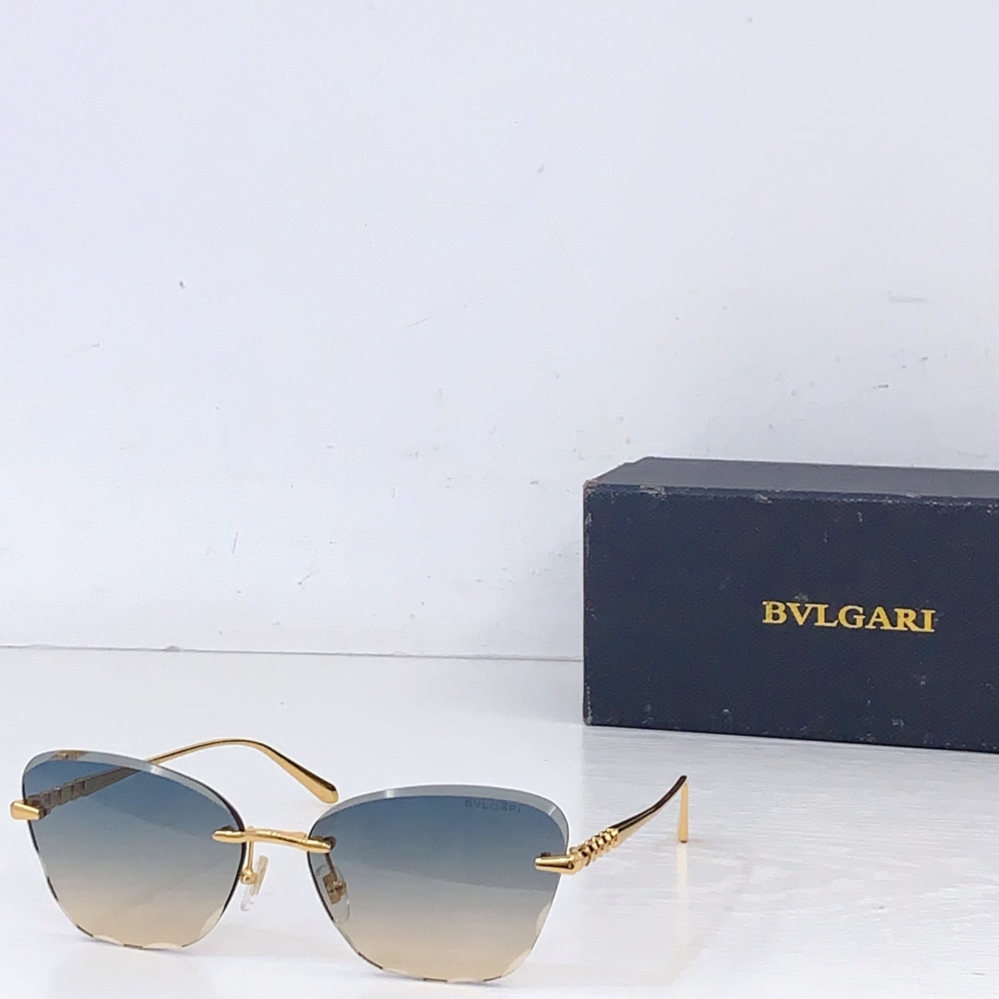 Bvlgari sunglasses with gold metal frame and light gold tinted lenses, front angle.