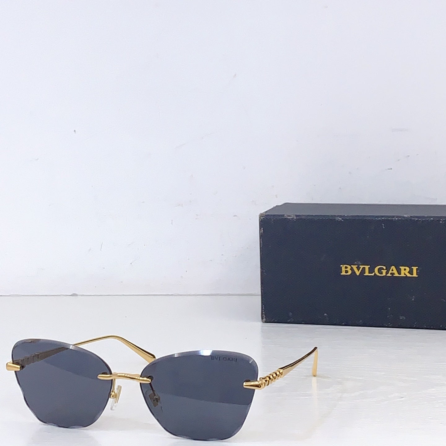 Bvlgari sunglasses with gold metal frame and dark gray lenses, front angle.