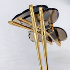Bvlgari sunglasses close-up of gold frame temples and dark lenses.