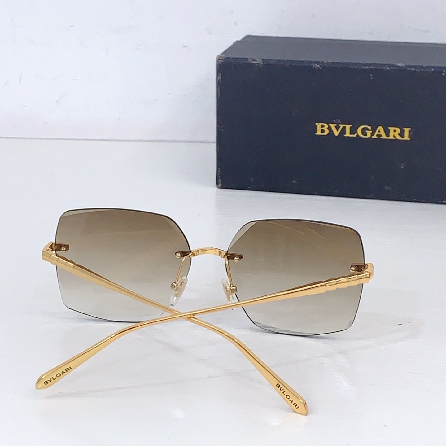 Bvlgari sunglasses with gold frame and light beige gradient lenses, crossed temples