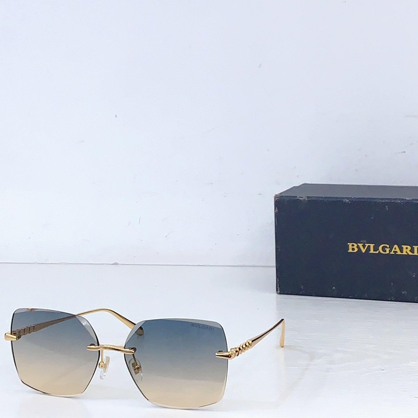 Bvlgari sunglasses with gold frame and gradient blue lenses, rectangular shield shape