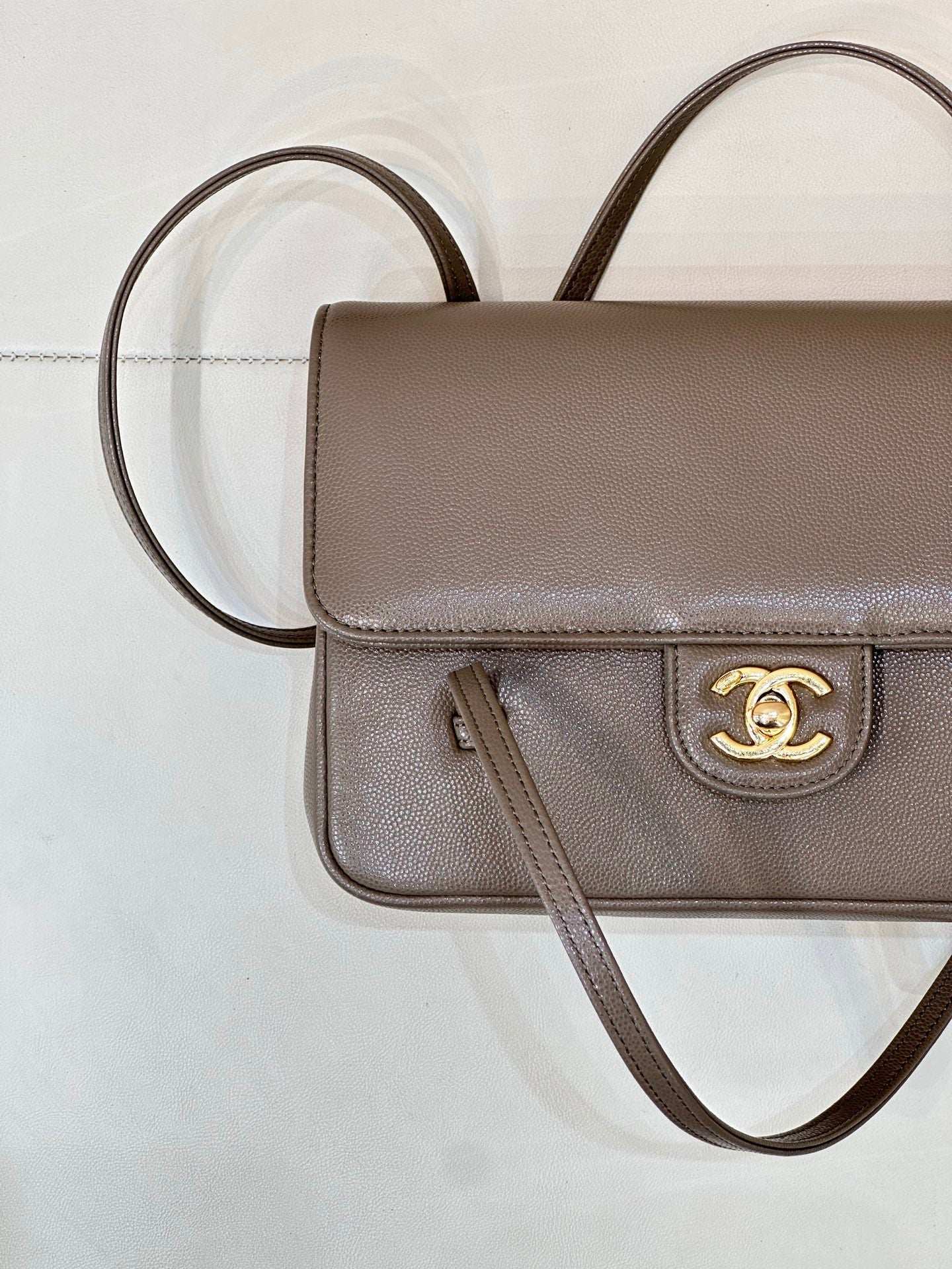 Taupe Chanel shoulder bag close-up of flap with gold CC logo and zipper pull
