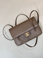 Taupe Chanel shoulder bag angled view with top handle, flap, and gold CC emblem