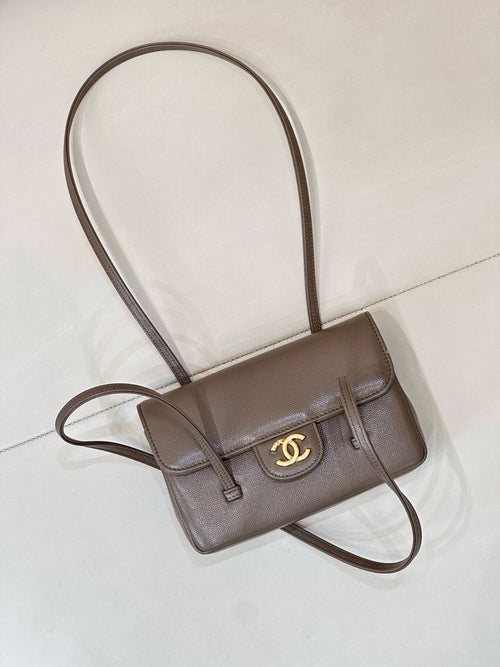Chanel bag in taupe leather with gold CC logo on front flap and adjustable crossbody strap.