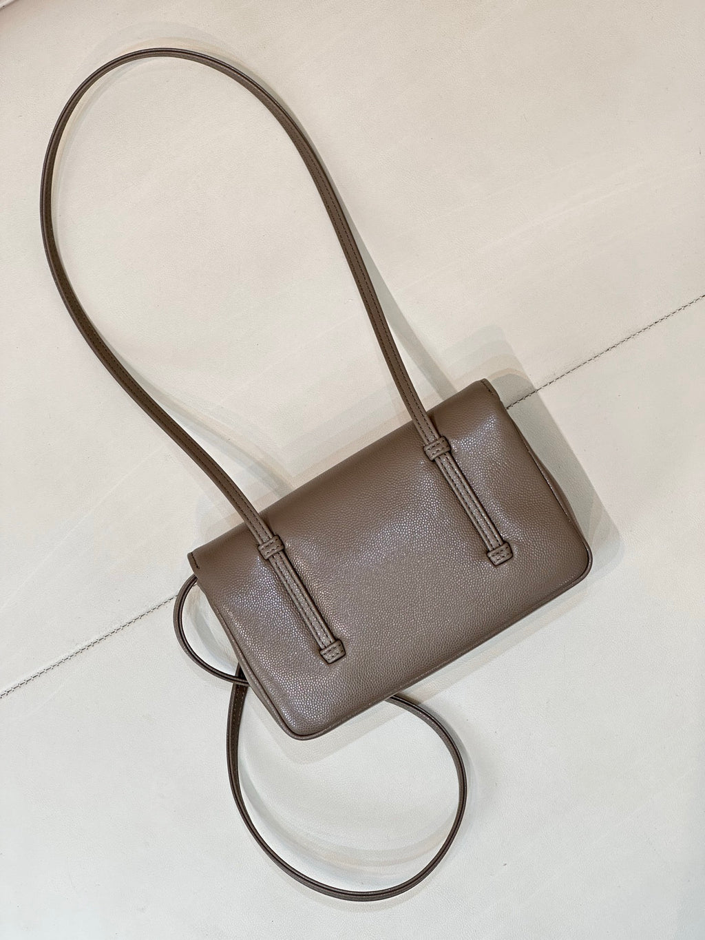 Chanel bag in taupe leather with long shoulder strap, structured body, and front flap.