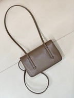 Chanel bag in taupe leather with long shoulder strap, structured body, and front flap.
