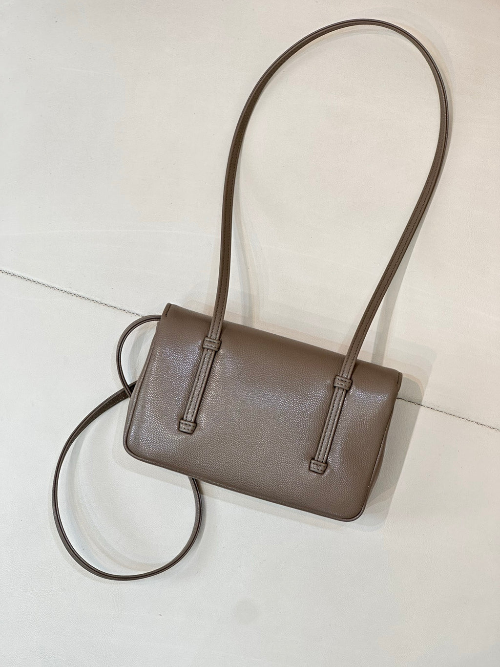 Chanel bag in taupe leather with two top handles and long crossbody strap attached.