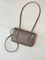 Chanel bag in taupe leather with two top handles and long crossbody strap attached.