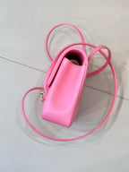 Pink mini handbag with open top, top handle, and long crossbody strap