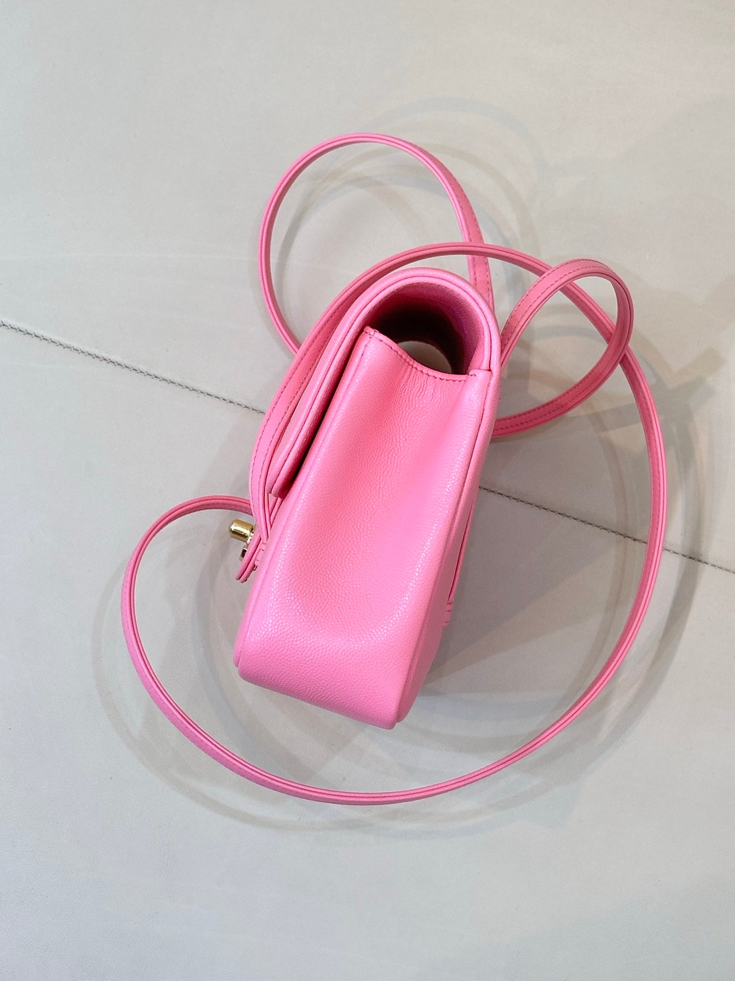 Pink mini handbag with open top, top handle, and long crossbody strap