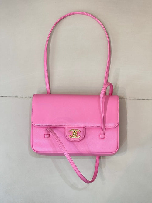 Pink flap handbag with top handle and crossbody strap, gold logo clasp