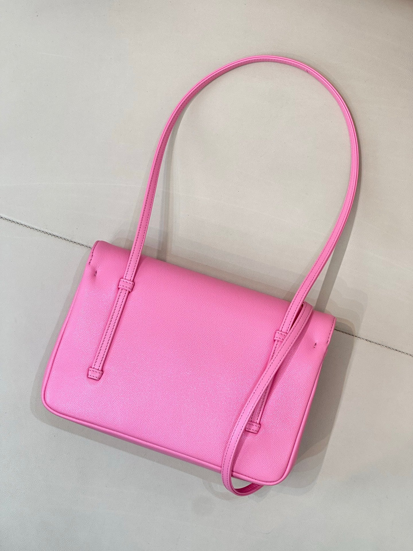 Pink structured handbag with top handles, stitched sides, and crossbody strap