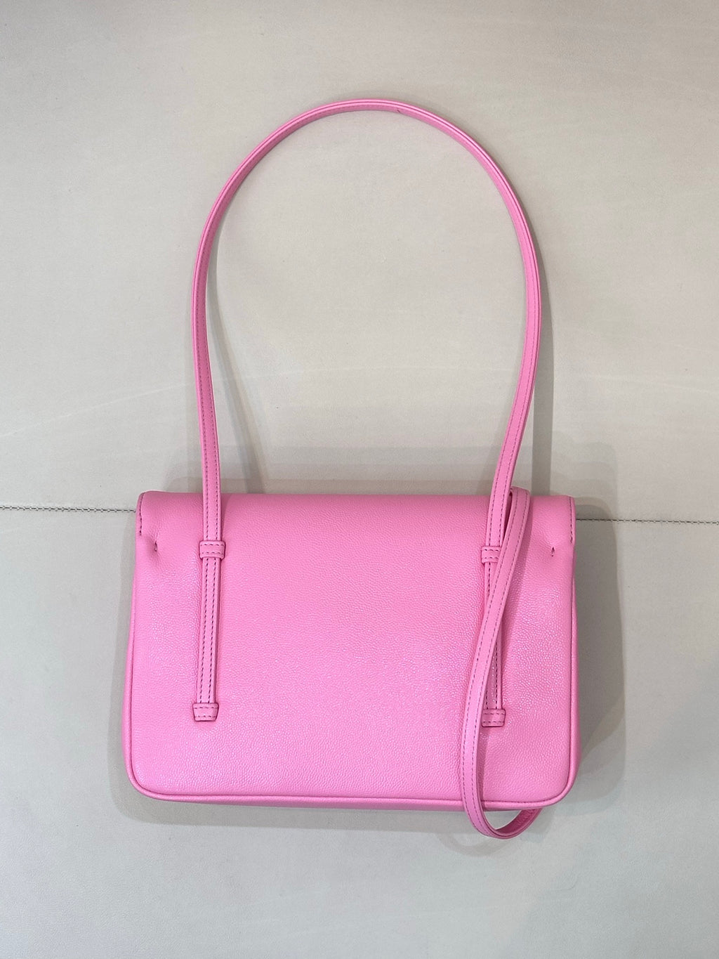 Pink structured handbag with top handles, front closure, and crossbody strap