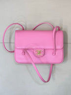 Pink flap handbag with front logo emblem and crossbody strap