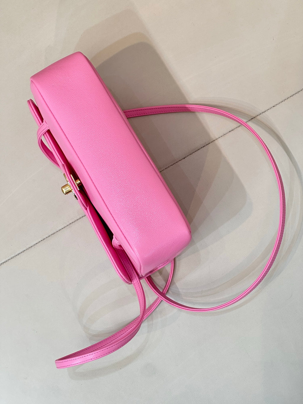 Pink slim handbag pouch with top handle, long shoulder strap, and side hardware