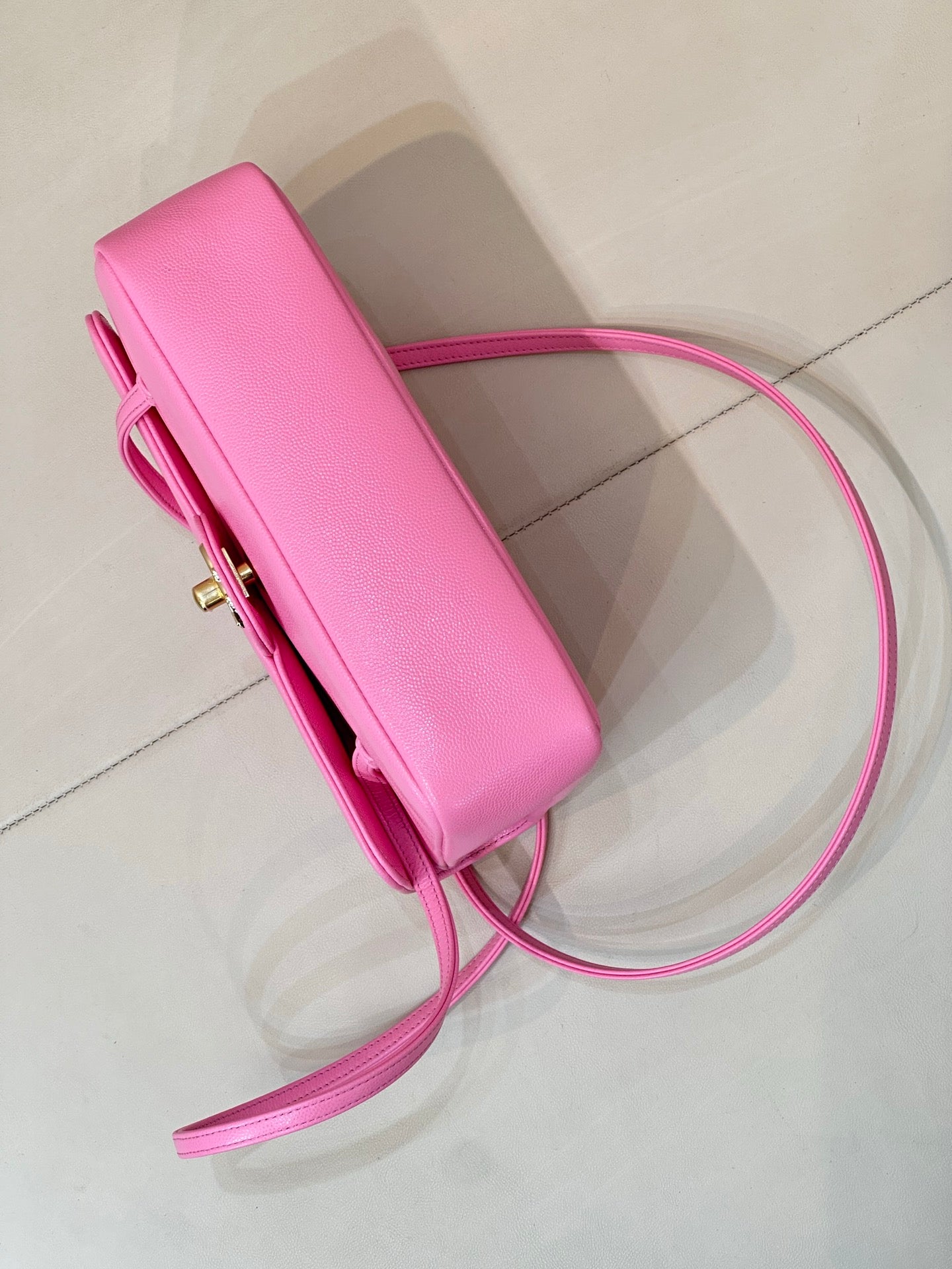 Pink slim handbag pouch with top handle, long shoulder strap, and side hardware