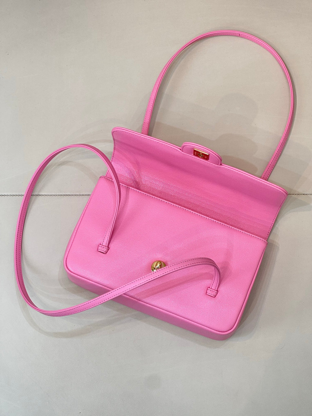 Pink mini handbag with open front, top handle, and long shoulder strap