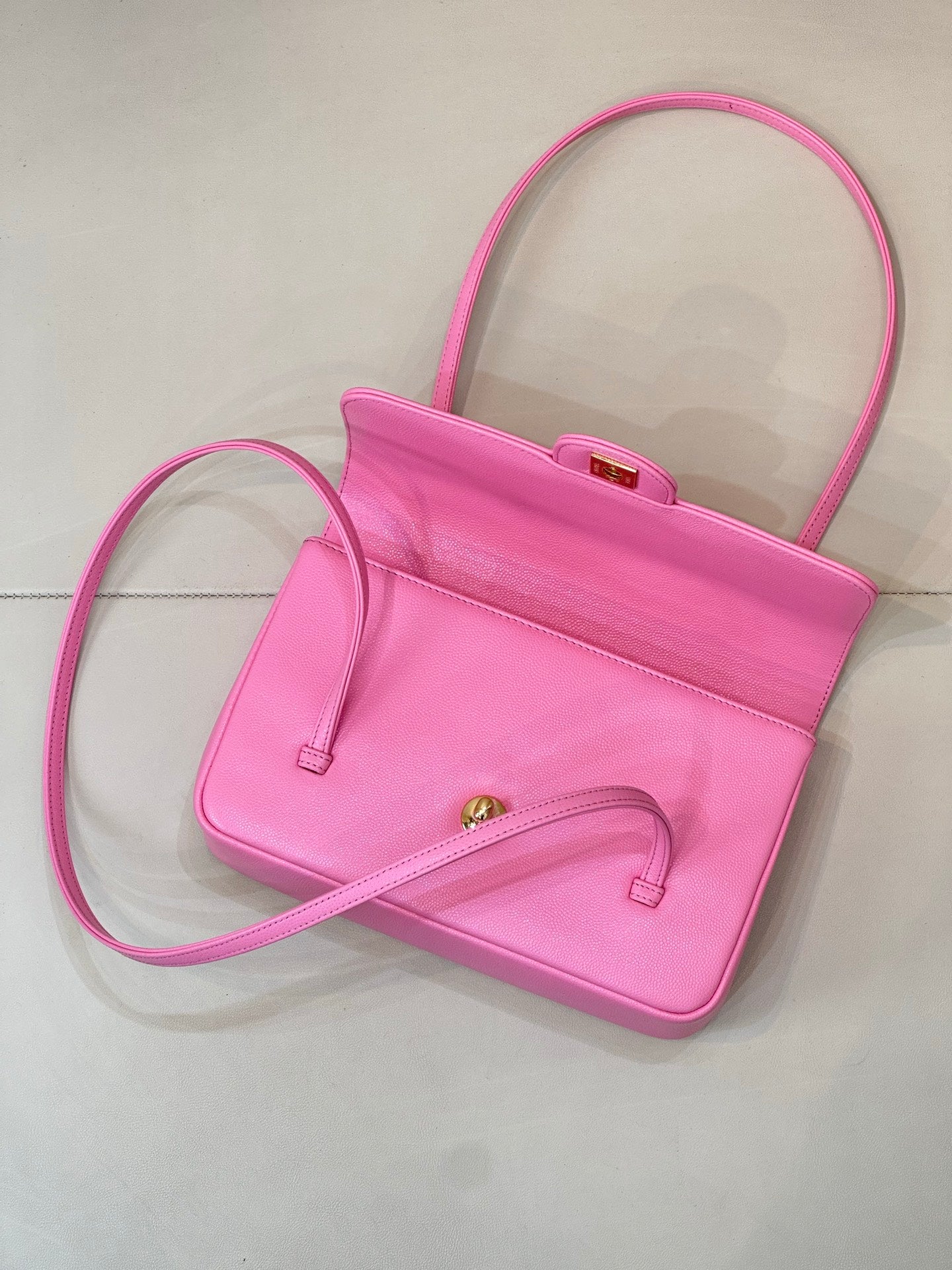 Pink mini handbag with open front, top handle, and long shoulder strap