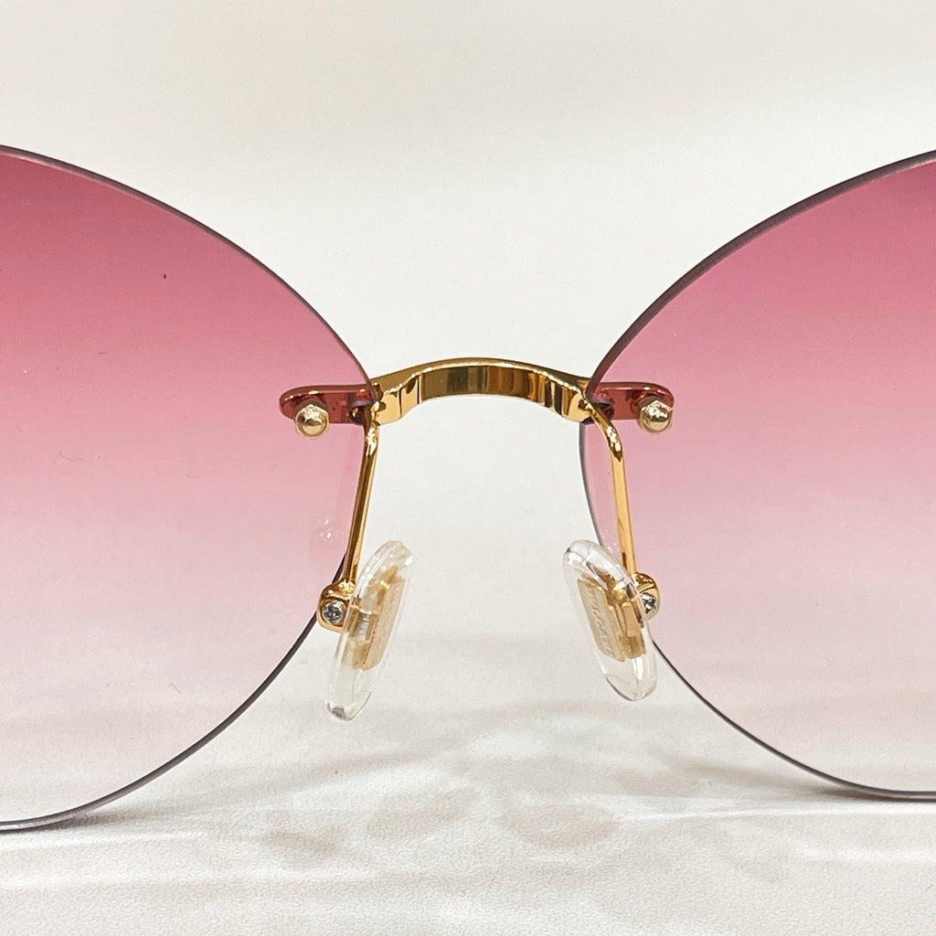 Sunglasses close-up with gold-tone frame and pink round lenses