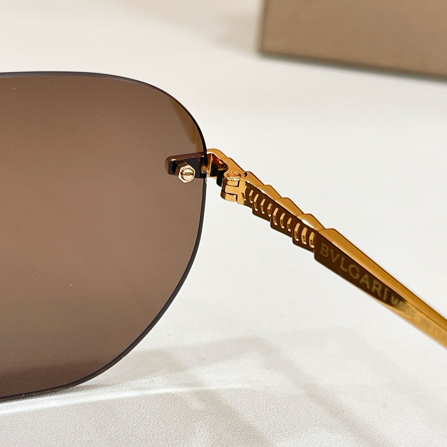 Close-up of gold Bvlgari sunglasses arm with dark round lens