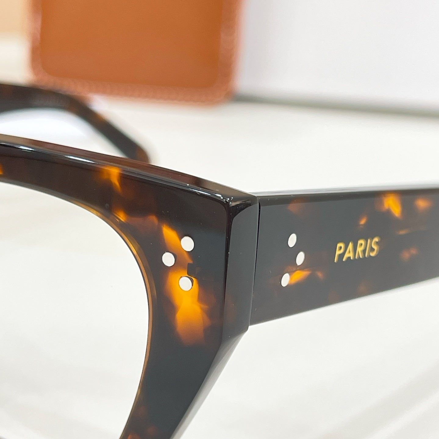 Celine glasses close-up of black temple with gold PARIS text and logo detail.
