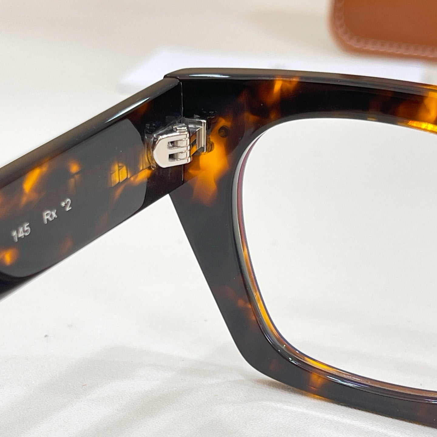 Celine glasses close-up of tortoise temple hinge and frame edge with metal rivet.