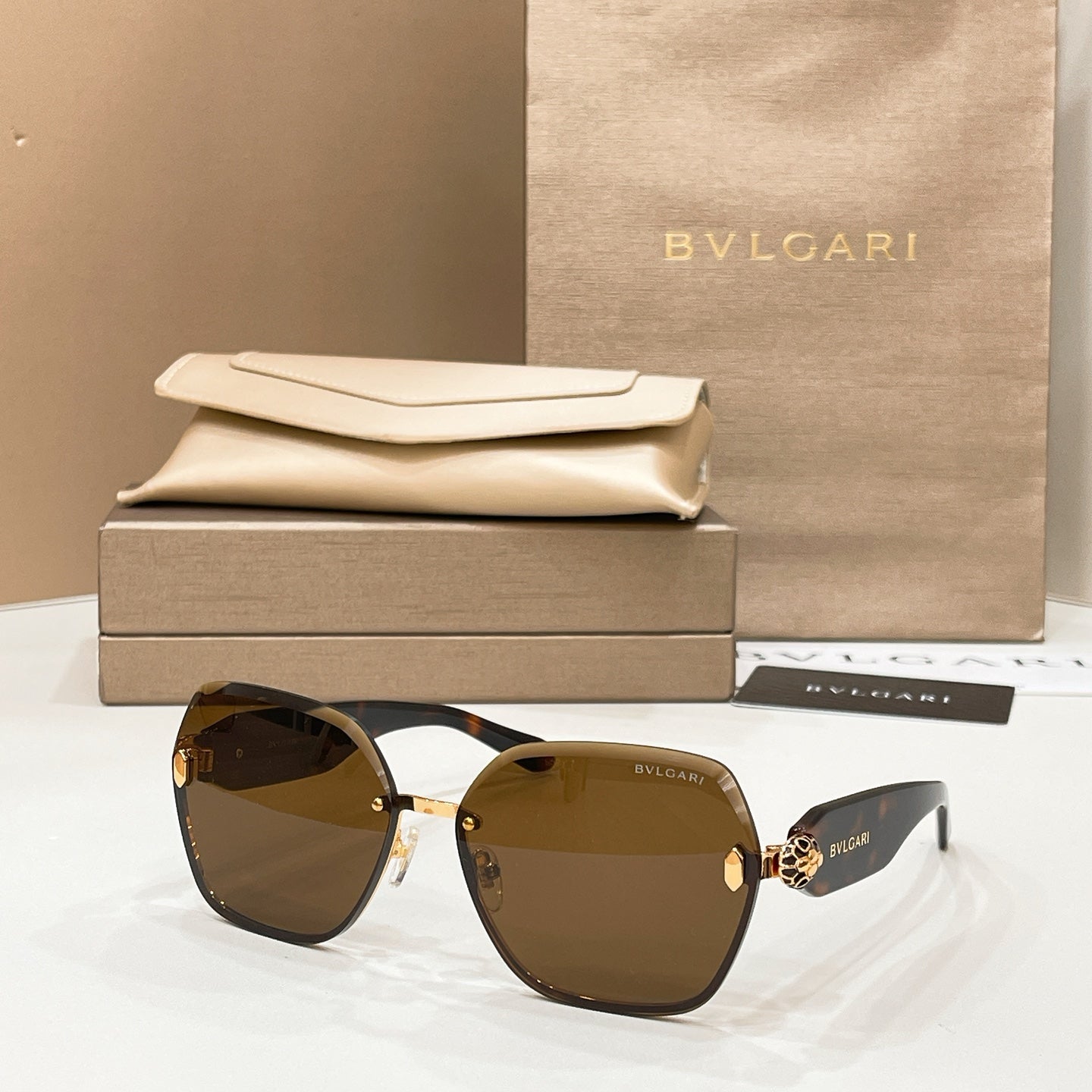 Bvlgari sunglasses with dark frames, gold accents, and brown gradient lenses