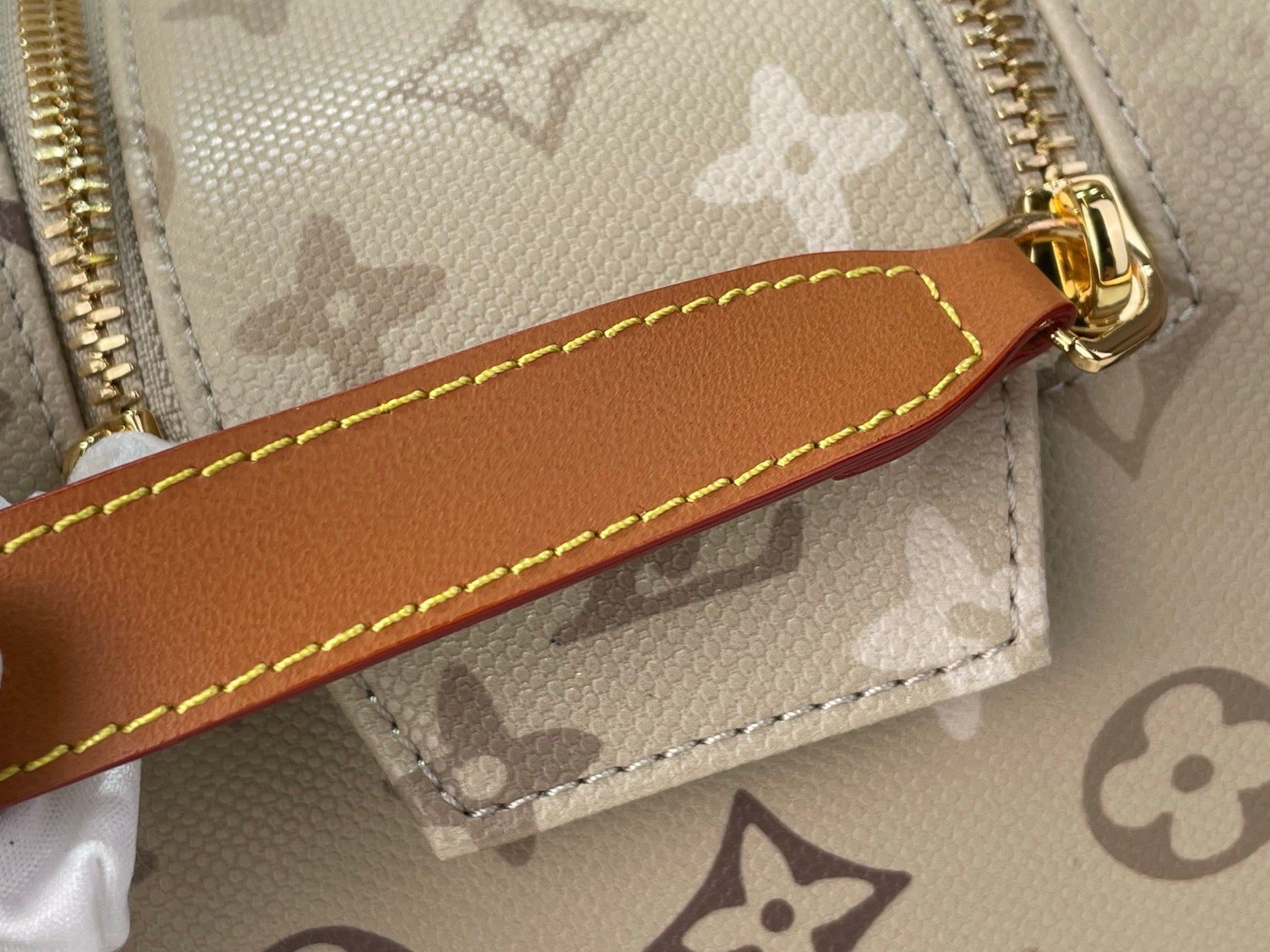 Louis Vuitton monogram bag leather zipper pull with tan stitching and gold hardware
