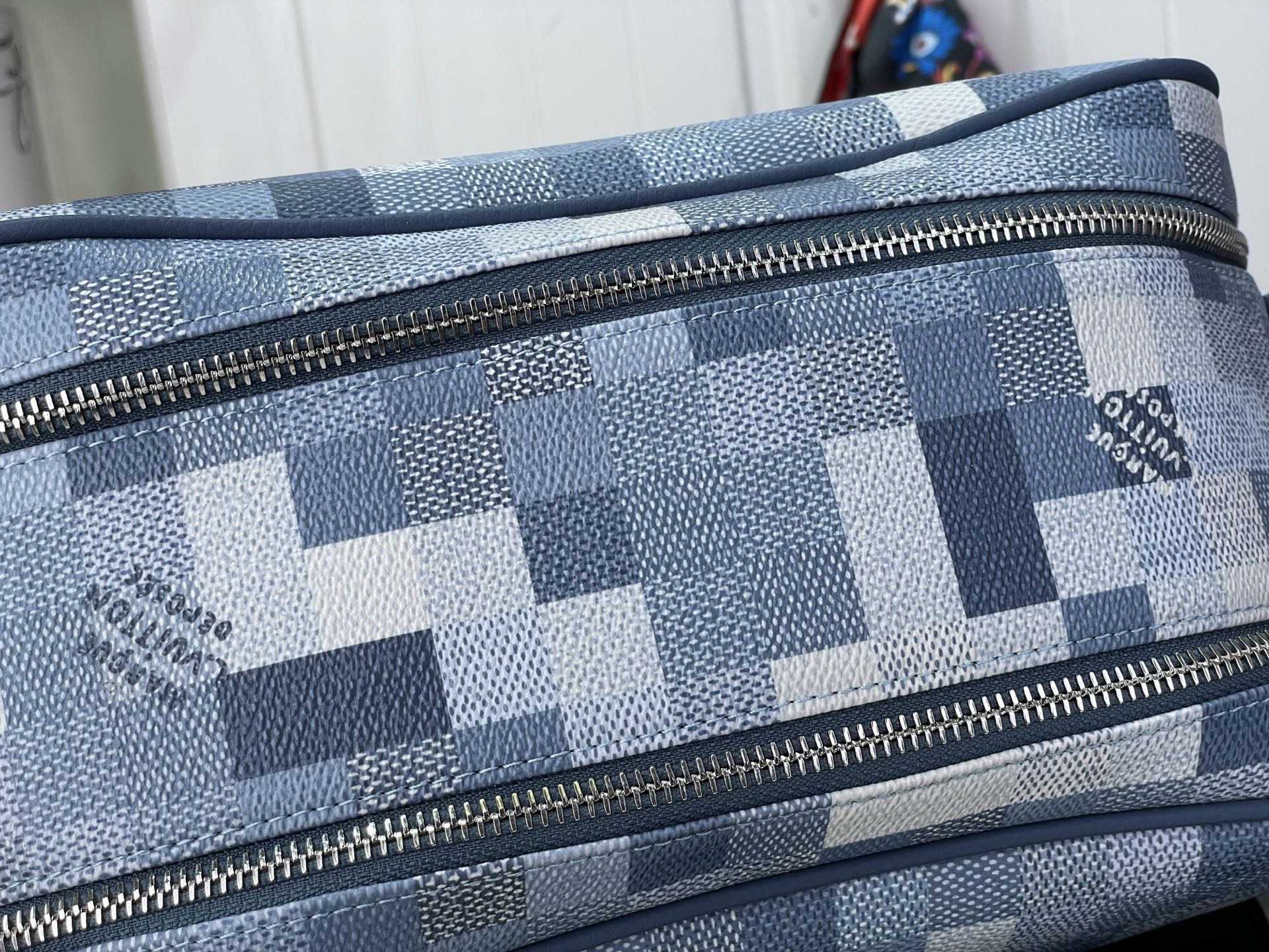 Checkered blue-and-white toiletry bag close-up of gold-tone zipper