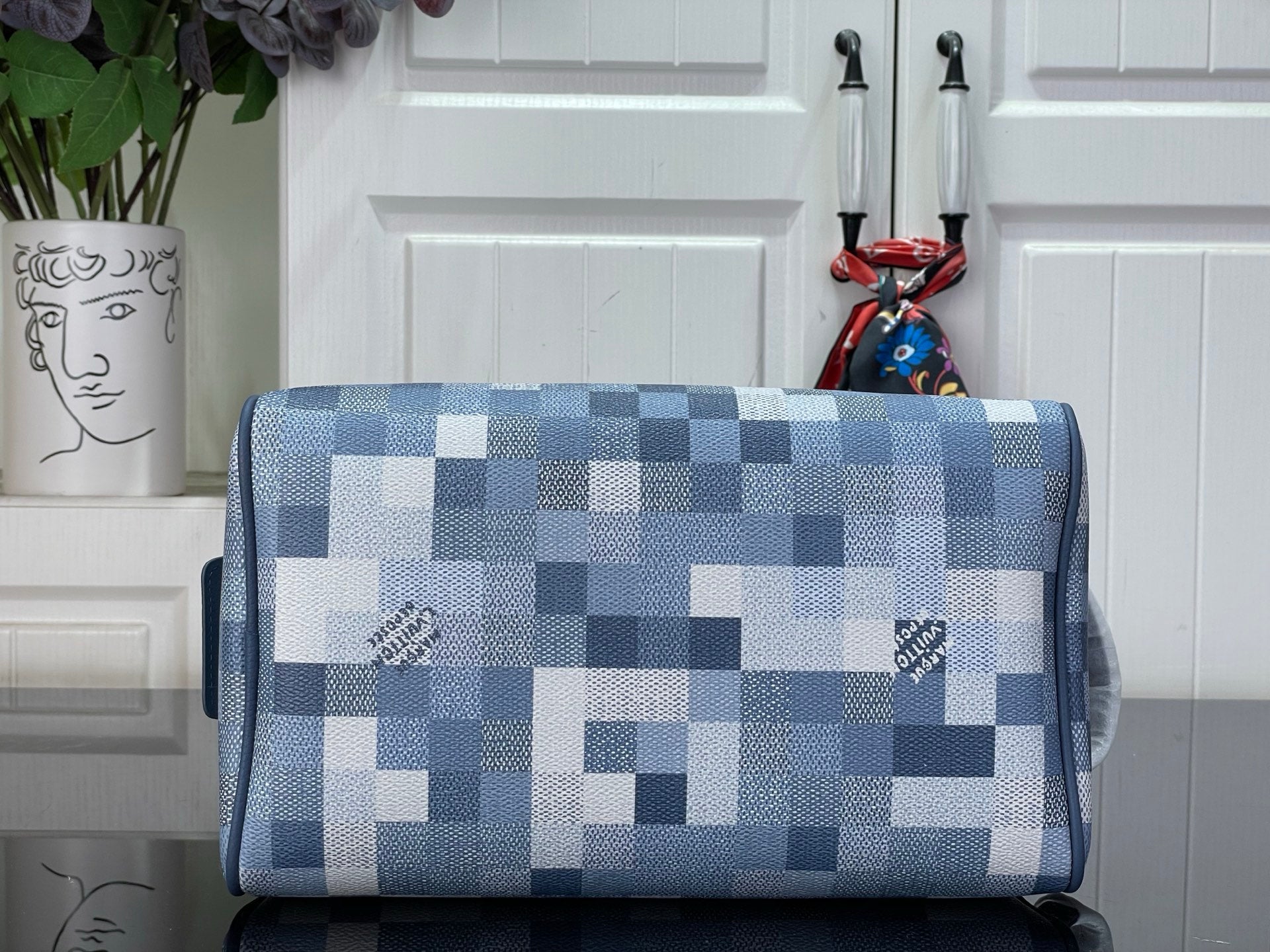 Checkered blue-and-white toiletry bag front with top zip and blue leather trim