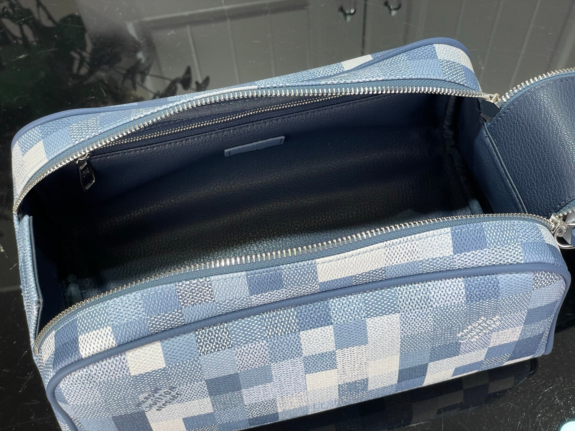 Checkered blue-and-white toiletry bag open with black interior and zip top