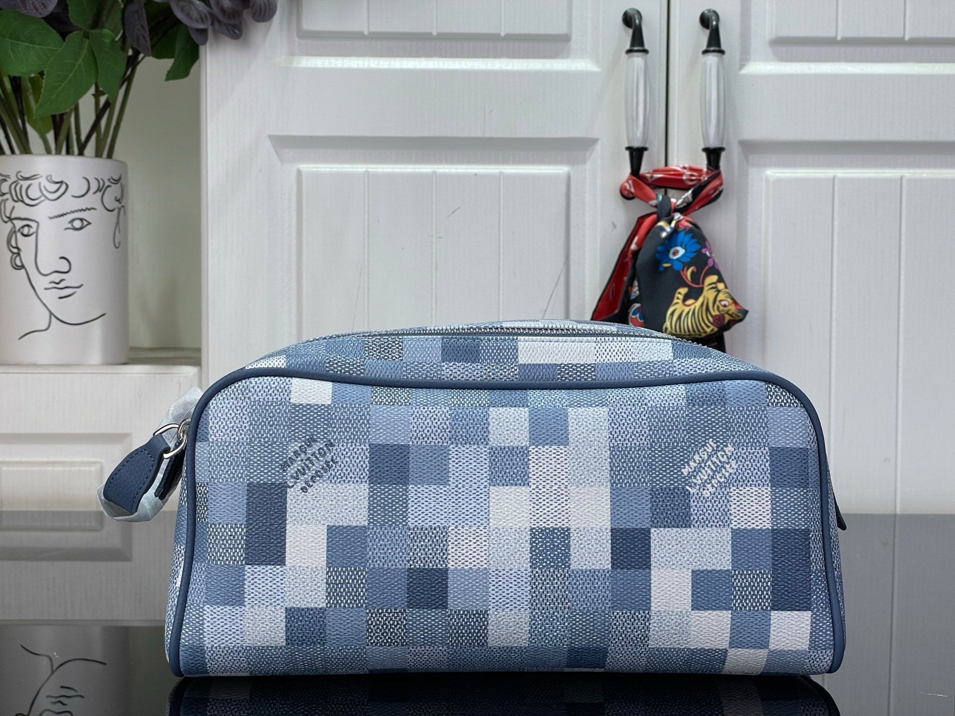 Checkered blue-and-white toiletry bag with top zipper and side handle