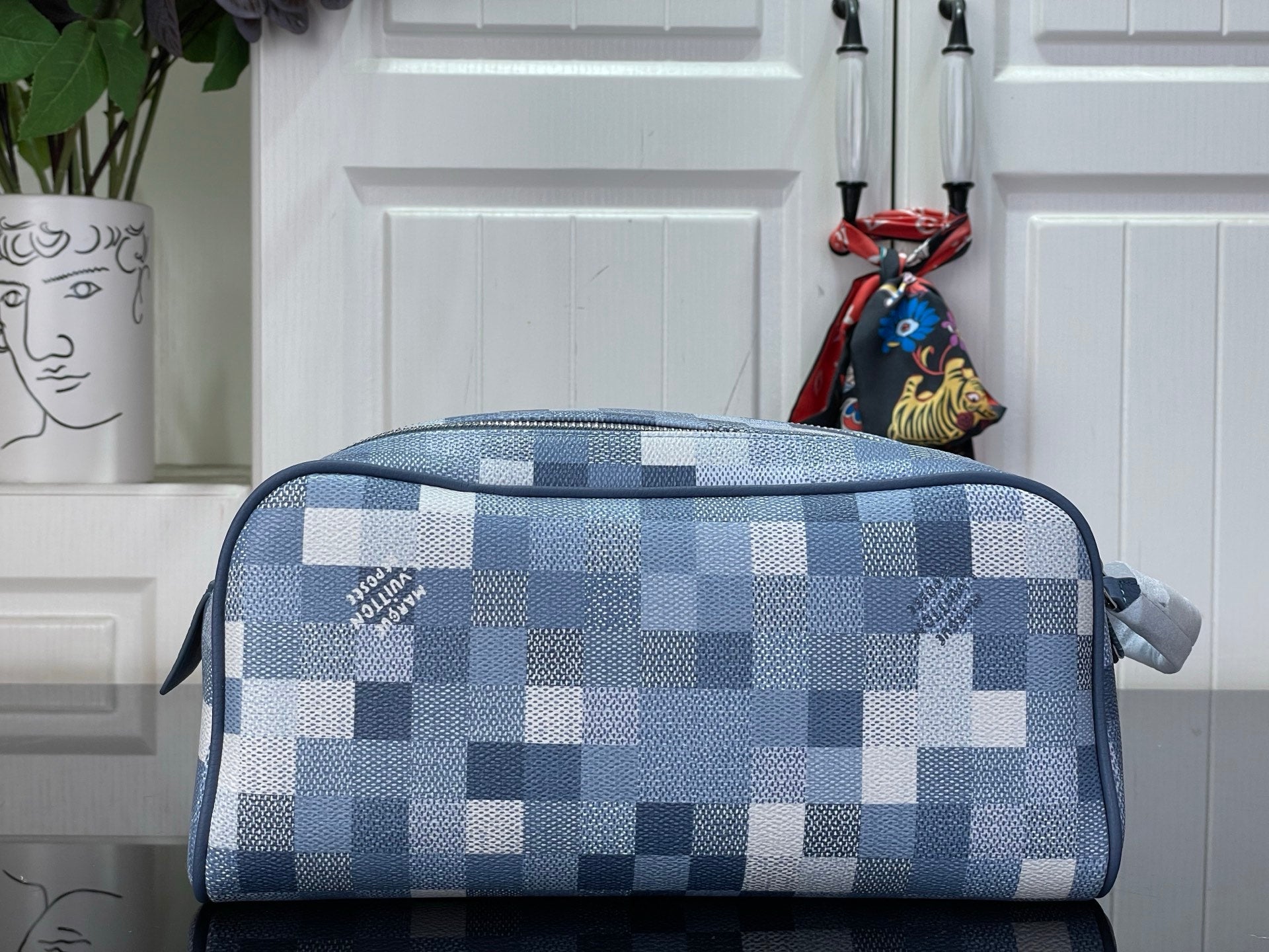 Checkered blue-and-white toiletry bag with zippered top and loop handle