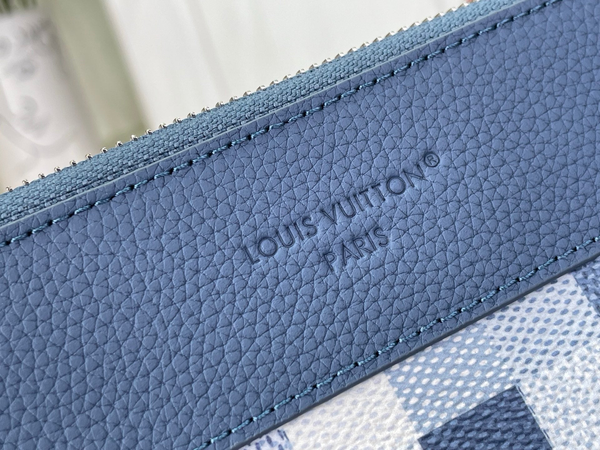 Blue leather trim on zip pouch with debossed Louis Vuitton Paris logo