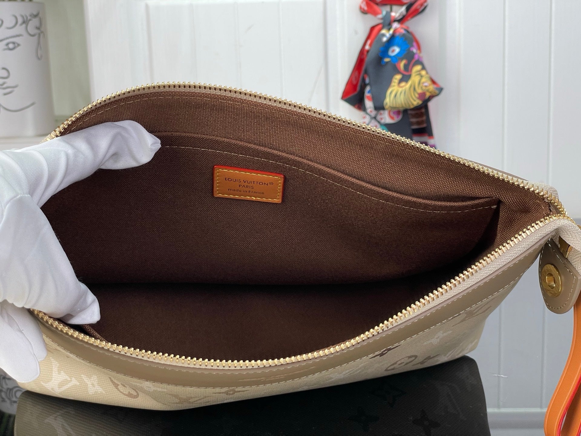 Open top-zip monogram bag with brown fabric lining and small interior label