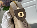 Tan leather loop with gold Louis Vuitton logo on monogram bag corner