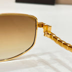Gold-tone sunglasses close-up: lens edge with hinge detail on temple