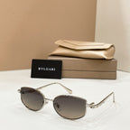 Gold-tone sunglasses with dark lenses, shown with beige case