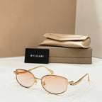 Gold-tone sunglasses with light brown lenses, shown with beige case