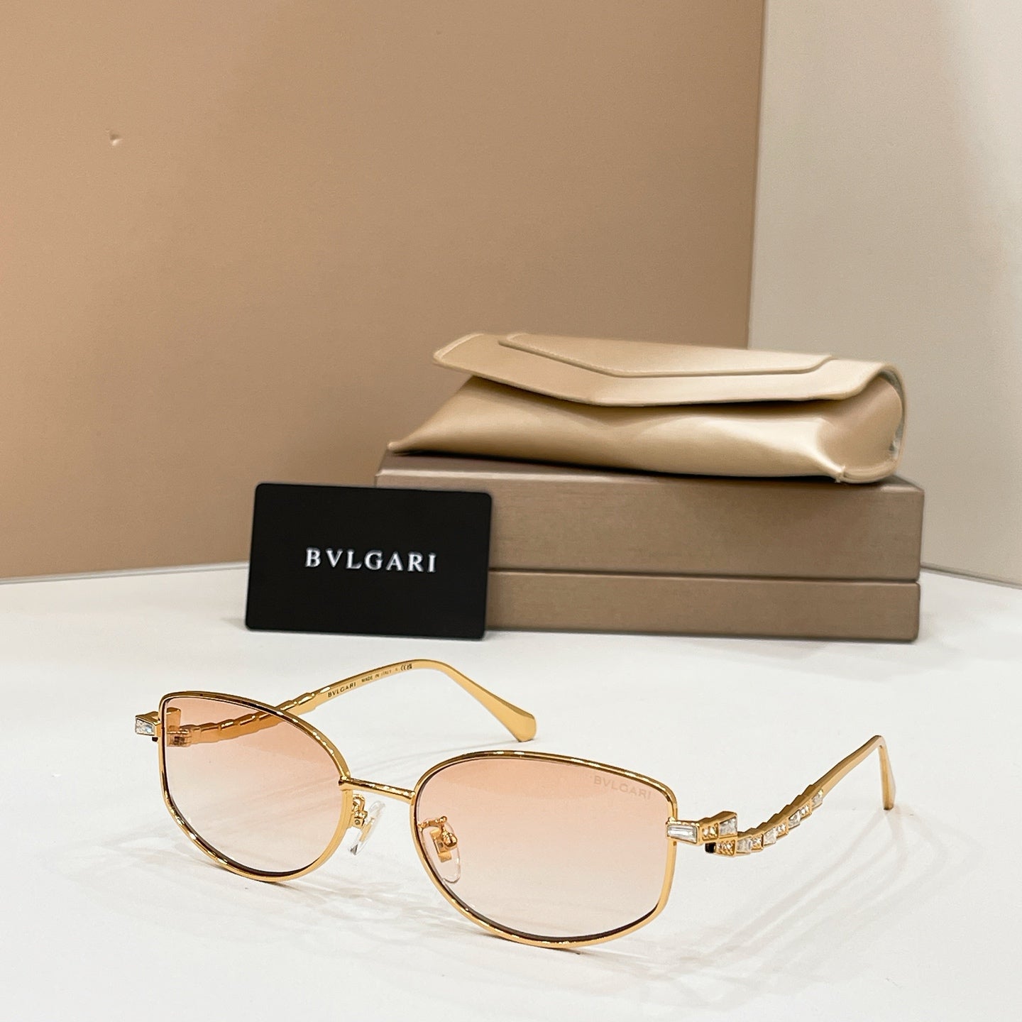 Gold-tone sunglasses with light brown lenses, shown with beige case