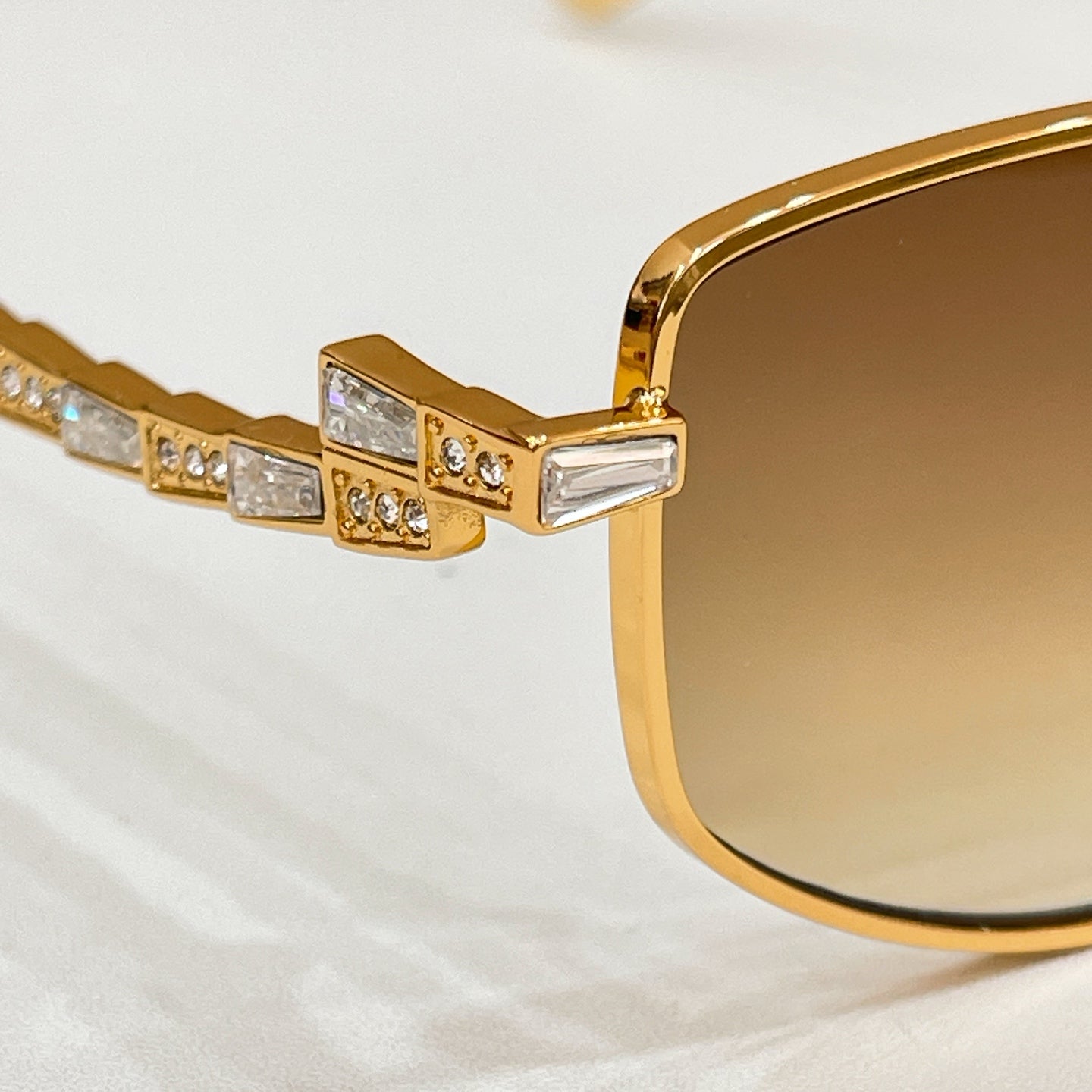 Gold-tone sunglasses close-up: rhinestone detail on temple and frame arm