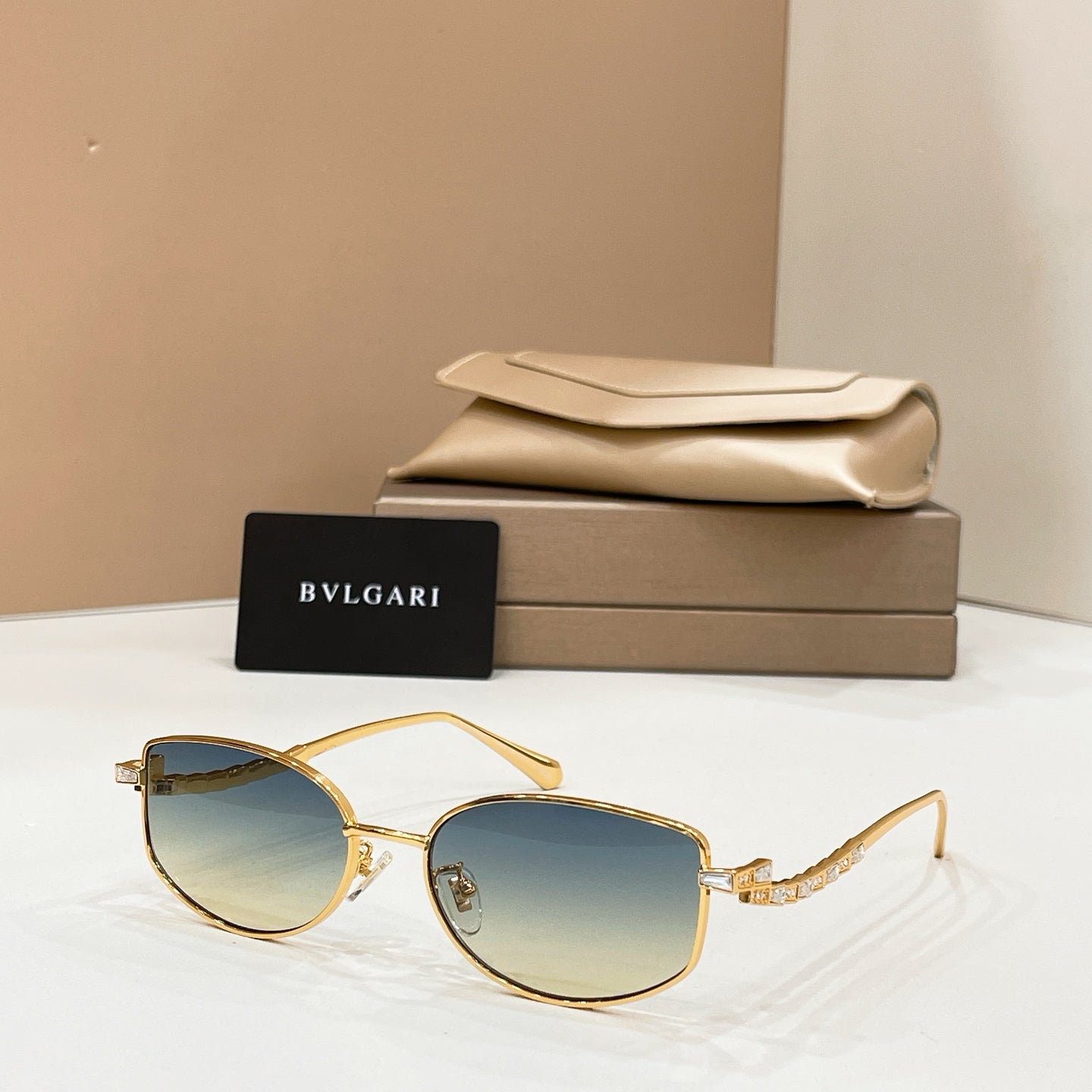 Gold-tone sunglasses with blue-tinted lenses, shown with beige case