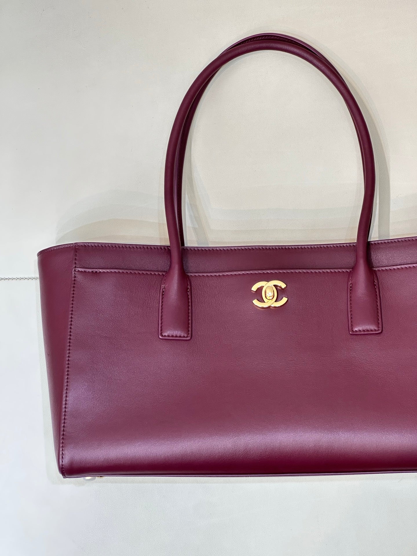 Chanel burgundy leather tote bag with front CC emblem and structured sides