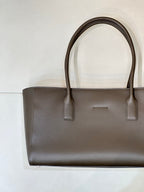 Taupe-brown leather tote bag front view with two top handles and minimal branding