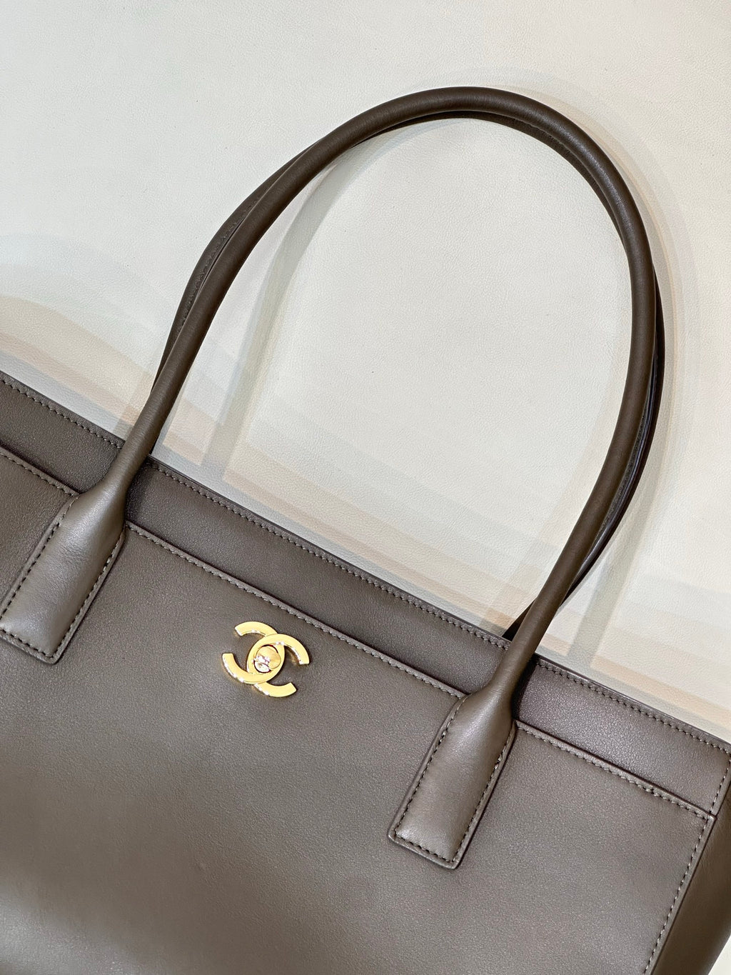 Taupe-brown leather tote bag front detail with stitched paneling and gold Chanel logo