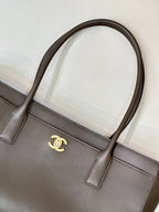 Taupe-brown leather tote bag front detail with stitched paneling and gold Chanel logo